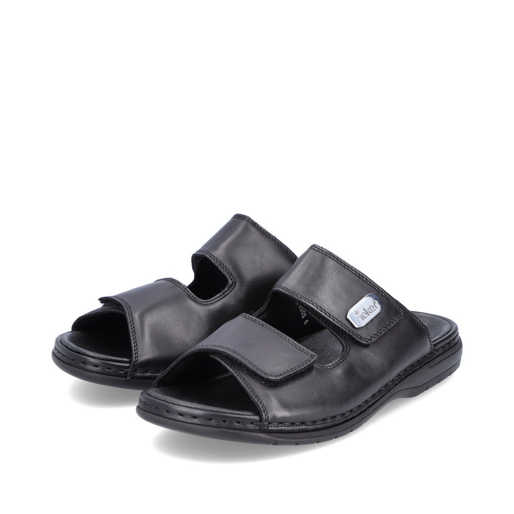 Black Rieker men´s mules 25590-00 with a hook and loop fastener. Shoes laterally.