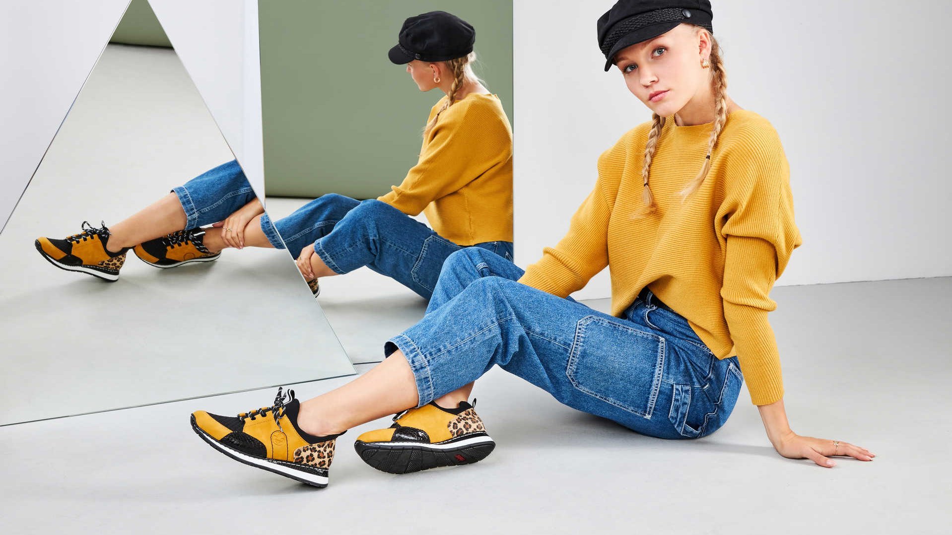 Eine junge Frau sitzt vor einem Spiegel und präsentiert ihre gelben Schuhe