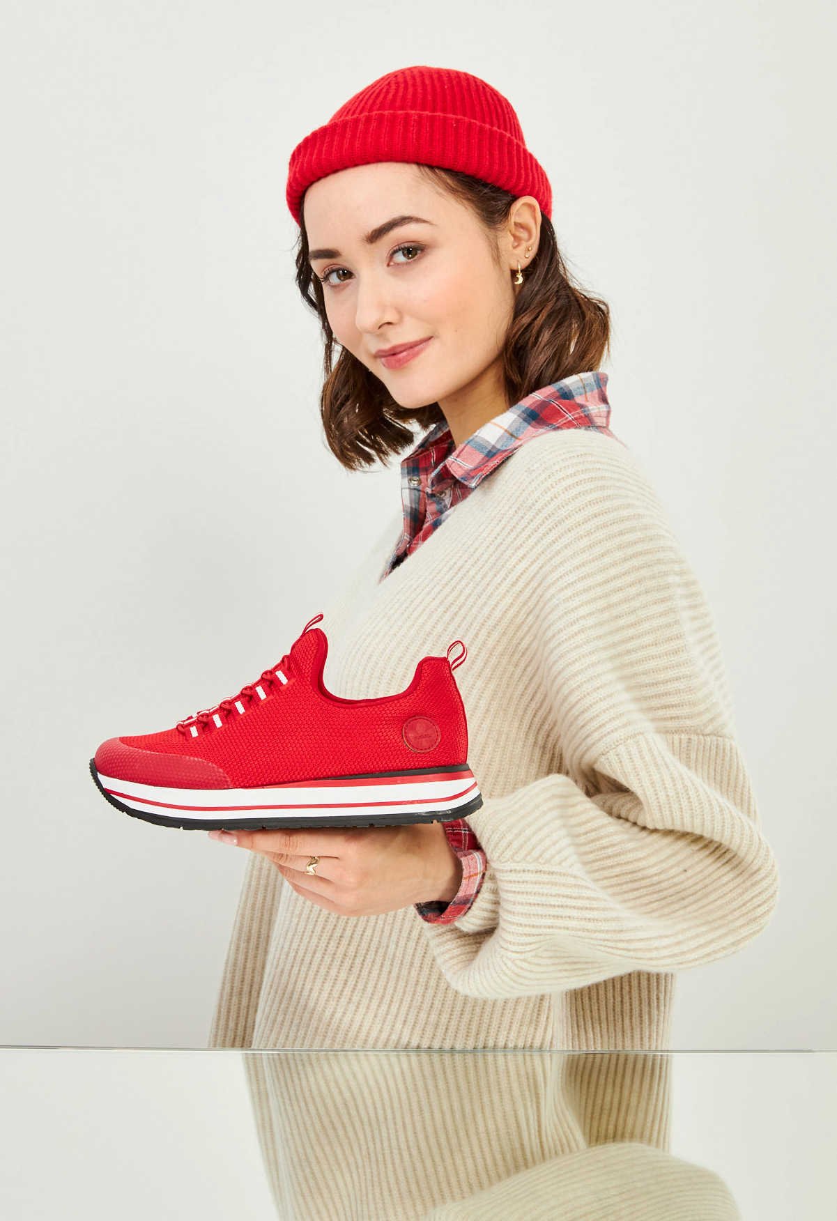 Eine junge Frau hält einen roten Schuh in das Bild