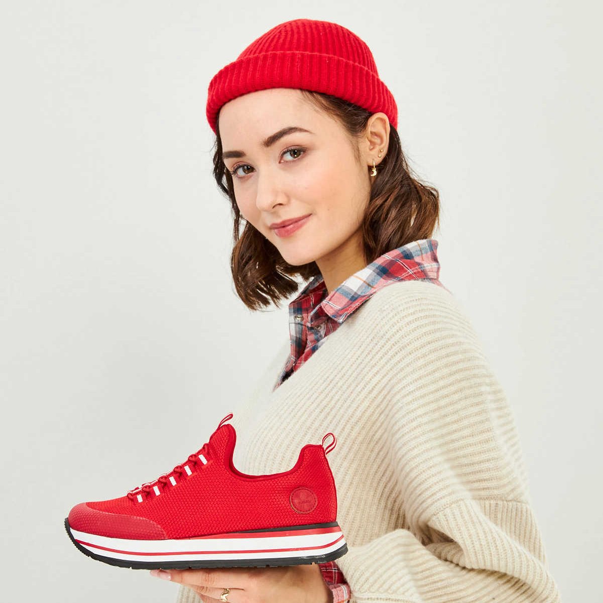 Eine junge Frau hält einen roten Schuh in das Bild