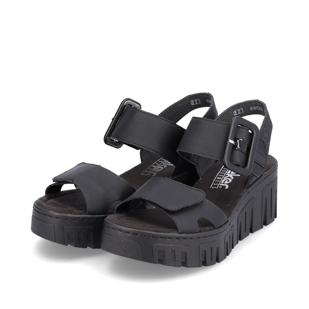 Rieker sandales compensées noires femmes 68050-00 avec fermeture velcro. Chaussures inclinée sur le côté.