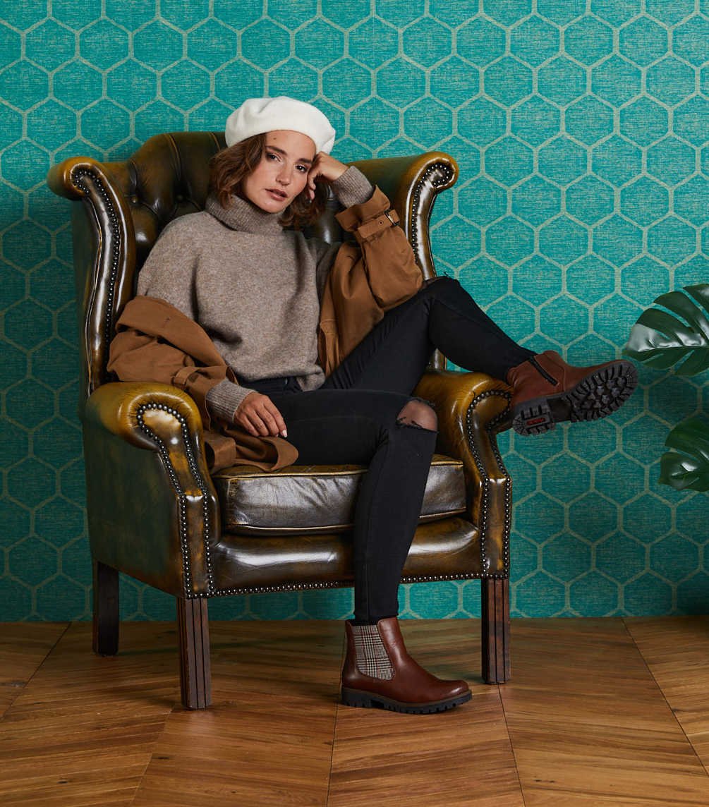 Eine Frau sitzt auf einem Lederstuhl mit braunen Schuhen