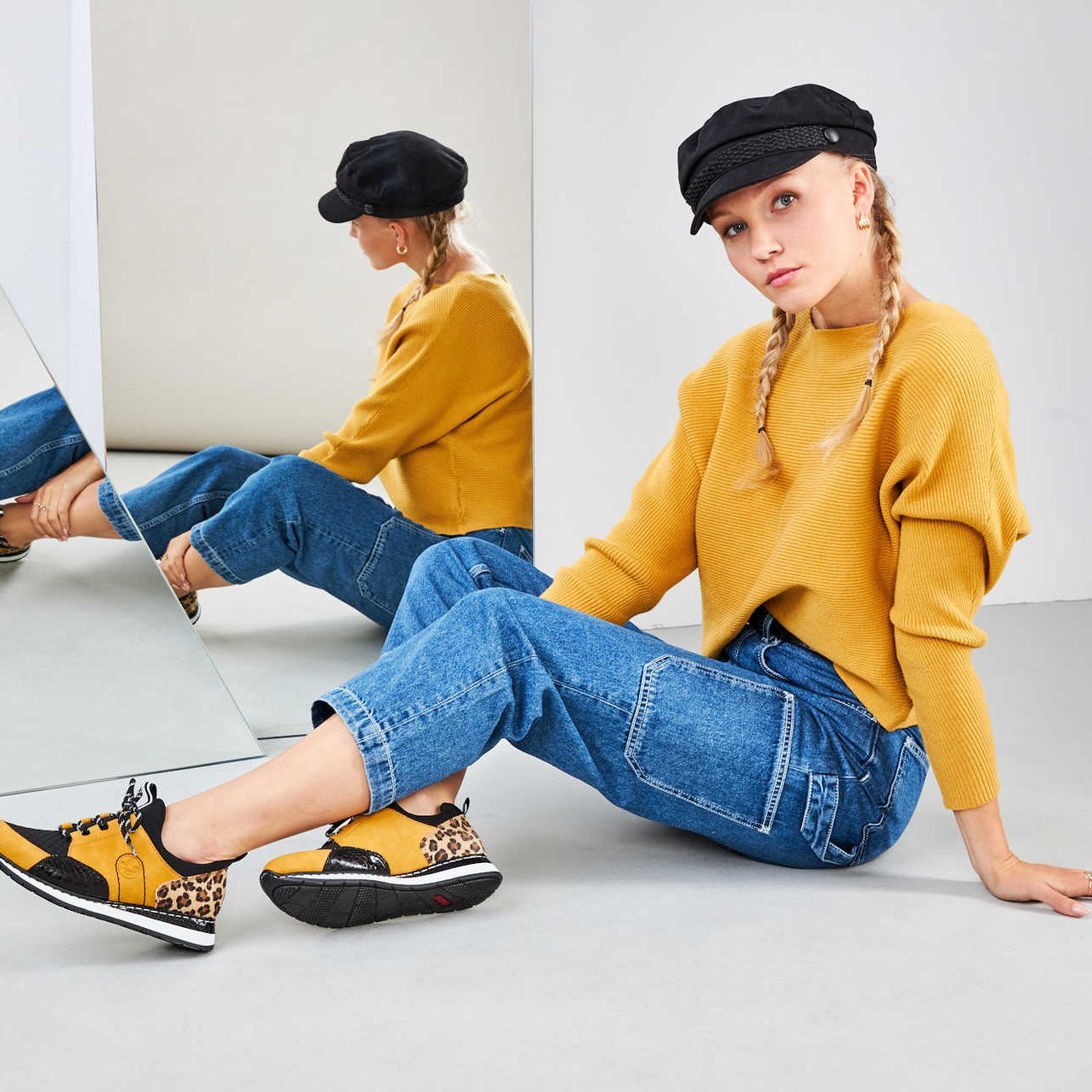 Eine junge Frau sitzt vor einem Spiegel und präsentiert ihre gelben Schuhe