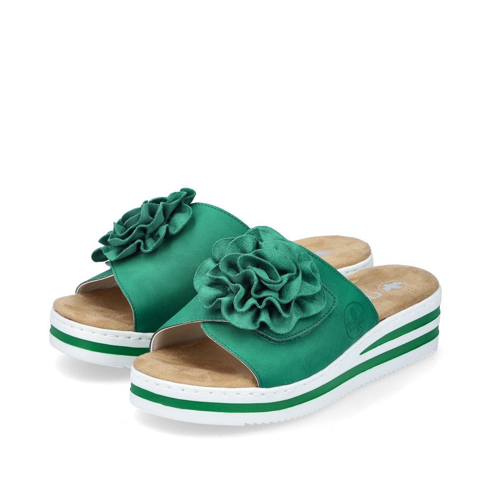 Grüne Rieker Damen Pantoletten V0252-52 mit Klettverschluss sowie Dekoblume. Schuhpaar seitlich schräg.